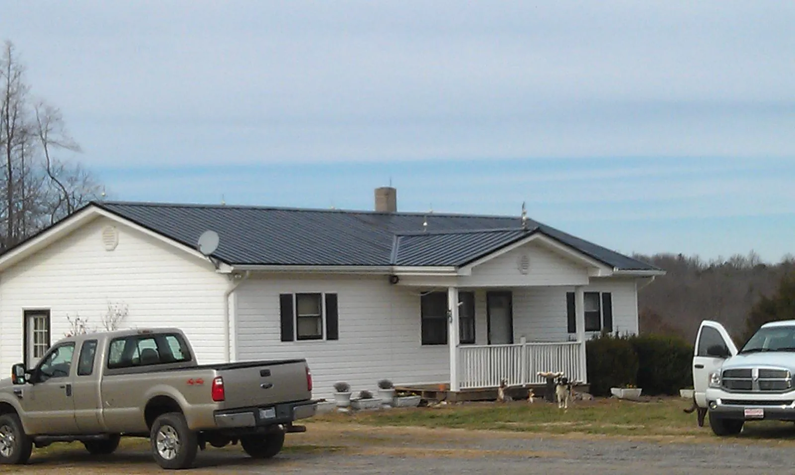 Finished dark metal roof on a white ranch home with work trucks parked in Cordova
