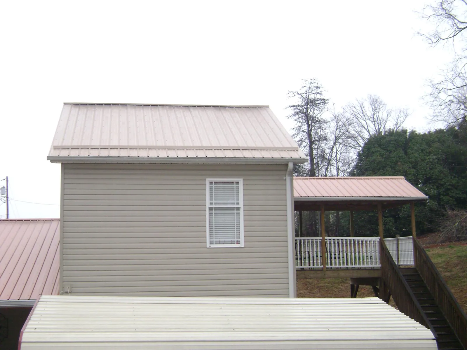 Tan metal roofs on a two story addition and attached porch, from a Roof Replacement job in Cordova